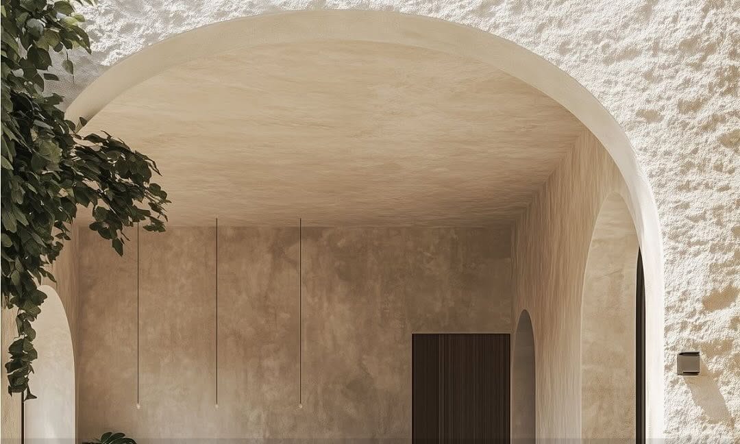 Moderni erdvė su arkine anga, augalais ir šviesia tekstūruota sienų apdaila – architektūrinio sprendimo pavyzdys